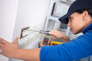 female electrician fixing socket to the wall