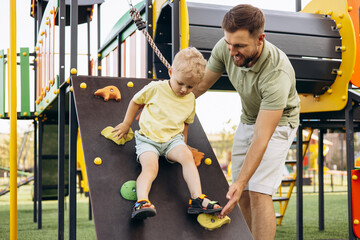 Boy with his father learning to climb at the playground