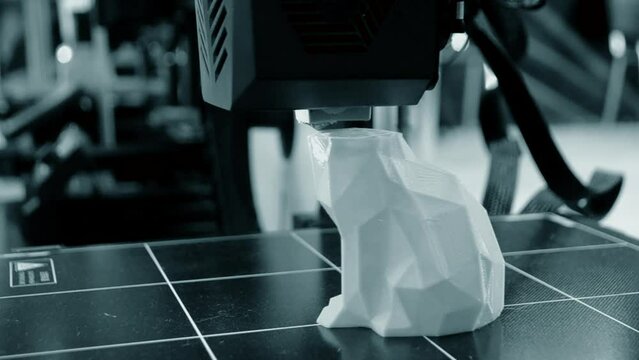 3D printer printing prototype of toy from molten plastic. Process of creating prototype model of toy on 3D printer from yellow melted plastic close-up. Additive new printer technology. Modern printing
