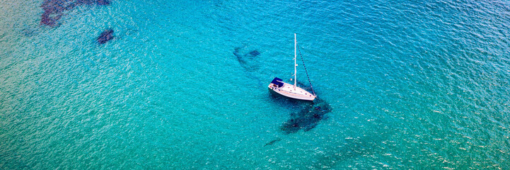 Yacht anchoring in crystal clear turquoise water in front of the tropical island, alternative...