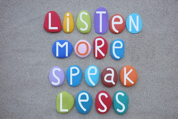 Listen more, speak less, lifestyle quote composed with multi colored stone letters over natural...