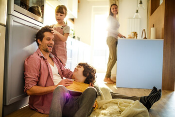 Young family being playful at home and using a digital tablet in the living room