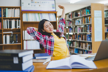 Students are relaxing after working on their laptops and searching for books to study, make reports, find useful information in the university room.