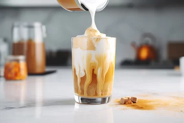Foto op Canvas Pouring milk into a glass with warm coffee drink with pumpkin spice or cinnamon, whipped milk foam and chocolate in a white sunlit modern kitchen interior. Generative AI technology © Romana