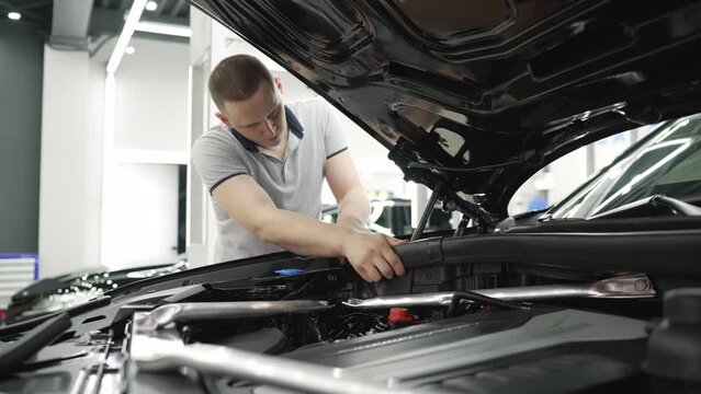 Car detailing, repair under the hood. Man working with parts under the hood. The master checks the car, under the soot.