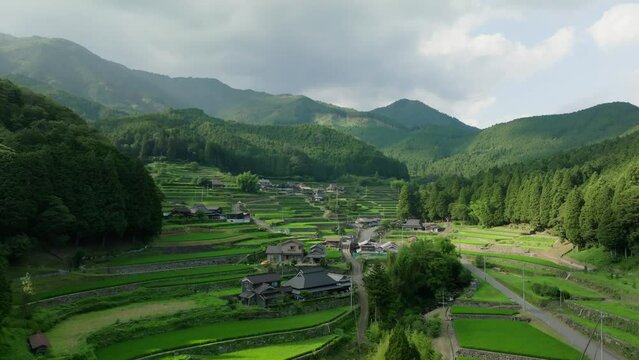 Slow rise over traditional homes by terraced rice fields in small village