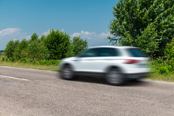 White car driving fast in countryside, motion blur