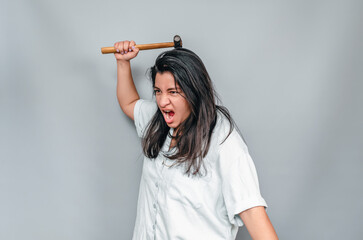 Side view woman in white shirt swings a hammer. Aggressive woman with a hammer.