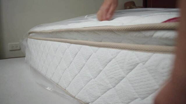 Man uncovering mattress in a bedroom