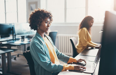 Young businesswoman and colleagues sitting at office desks and working on computers