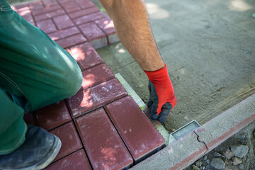 During the laying of paving blocks, the worker checks with a protractor, the correctness of the workmanship.