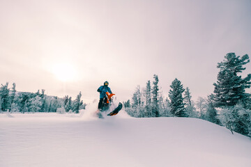 Snowbike rider in mountain valley in beautiful snow powder. Modify dirt bike with snow splashes and trail. Snowmobile sport riding, winter sunny day