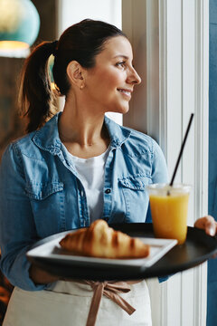Smiling cafe waitress carrying a tray of food