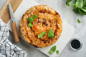 Delicious pie Spanakopita with soft feta cheese and spinach on old gray concrete table backgrounds. Traditional Greek Spiral filo pastry pie spanakopita in shape of roll. Traditional Greek cuisine.