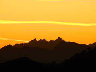 Silueta de montaña en diferentes grises, bajo un cielo amarillento del atardecer