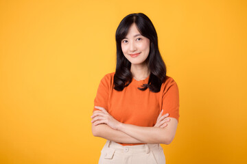 Obraz premium Radiate confidence like a young Asian woman in her 30s, wearing an orange shirt, displaying crossed arm sign gesture on yellow background.