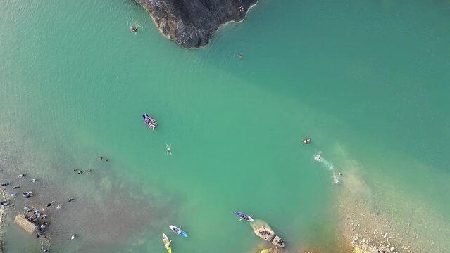 Aerial view of canoe boats in mountain river with turquoise water with rock cliffs. People kayaking, canoeing, and swimming in Kedung Jati Parang, Selopamioro, Imogiri, Bantul, Yogyakarta. 4k footage