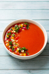 Spanish tomato gazpacho cold soup styled and decorated in white plate on wooden table