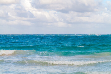 Ocean view with shore waves under blue cloudy sky on a sunny day