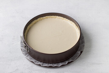 Cheesecake making, metal detachable baking dish with shortcrust pastry for cheesecake or other pie. Step by step, cooking stage, home baking, light gray background