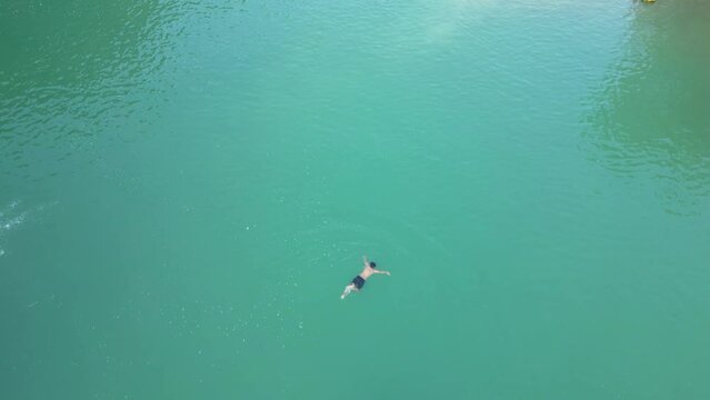 Aerial view of canoe boats in mountain river with turquoise water with rock cliffs. People kayaking, canoeing, and swimming in Kedung Jati Parang, Selopamioro, Imogiri, Bantul, Yogyakarta. 4k footage