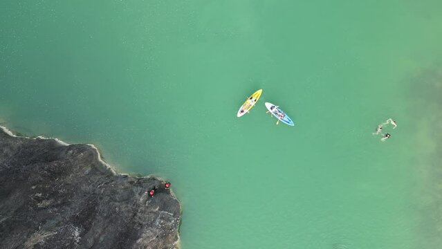 Aerial view of canoe boats in mountain river with turquoise water with rock cliffs. People kayaking, canoeing, and swimming in Kedung Jati Parang, Selopamioro, Imogiri, Bantul, Yogyakarta. 4k footage