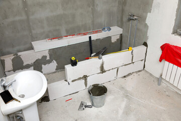 Interior of a new bathroom with the concrete blocks and construction tools.