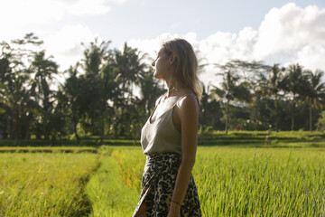 Outdoor fashion portrait of young woman in the rice field on the tropical island, natural sunlight....