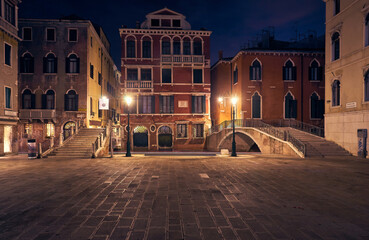 beautiful architecture of Venice, Italy, by night with a little bridge over a canal lit up by streetlight