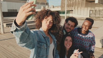 Young cheerful people make a joint selfie. Group of students smiling while looking at mobile phone...