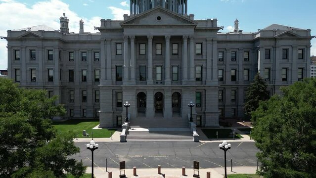 This is a liftoff shot which reveals downtown Denver and the Rocky Mountains from behind the capital building.