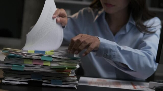 Young adorable Asian businesswoman working with work document during the night, working overtime at night.