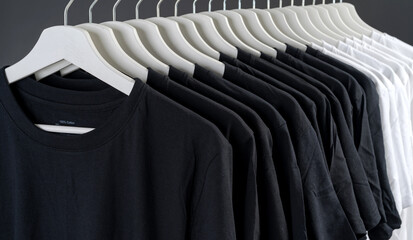 close up collection of black and white color t-shirt hanging on wooden clothes hanger - obrazy, fototapety, plakaty