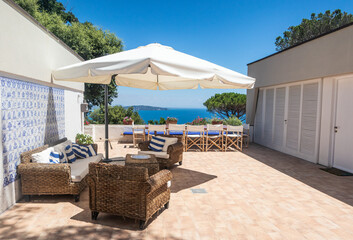 Luxury sea holidays mansion real estate, patio with couch table and chairs, beautiful sea view, bright summer day