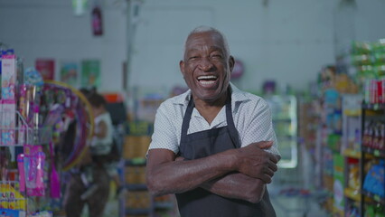 Happy African American employee and female customer laughing and smiling together standing by supermarket aisle. joyful authentic everyday people