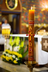 Front view of baptism gold candle with flame close-up from  catholic or orthodox church