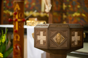 Front view of baptismal font and gold candle with flame close-up from  catholic or orthodox church
