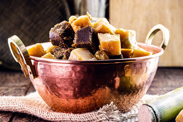 Candy in a copper pot on a rustic table. Rapadura is a sugar cane-based sweet, of African origin...