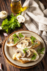 Homemade bruschetta with mushrooms. Toasted sandwich from baguettes bread with soft cheese and grilled mushrooms on wooden rustic table.