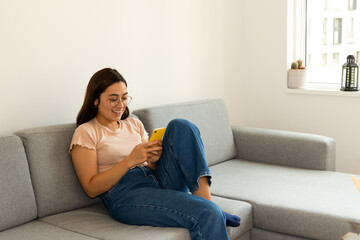 Obraz premium woman sitting comfortably on the sofa using the cell phone