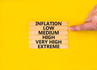 Low inflation symbol. Concept word Inflation low medium high very high extreme on wooden sticks. Businessman hand. Beautiful yellow background. Business time to low inflation concept. Copy space.