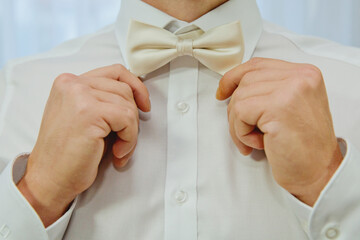Man fixing his bow tie. Man groom in wedding suit with a bow tie. Close-up. - Powered by Adobe