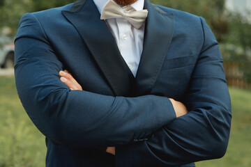 Groom with arms crossed in nature. Close-up.