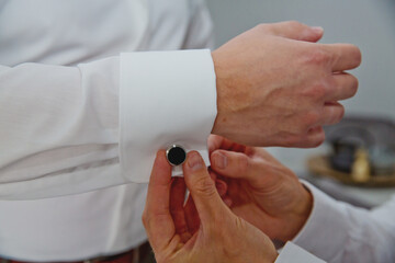 Obraz na płótnie Canvas A groom putting on cuff-links. Groom's suit.