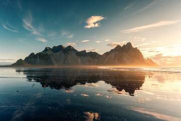 Sunrise over Vestrahorn mountain with reflection on black sand beach in summer at Iceland