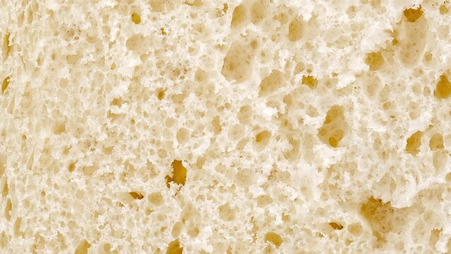 Bread, slice, inner part baked dough with pores rotating, turning, close-up macro, top view
