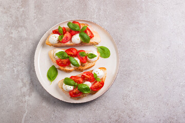Tomato, basil and mozzarella cheese fresh made caprese bruschetta. Italian tapas, antipasti with vegetables, herbs and oil on grilled ciabatta and baguette bread. Open sandwich.