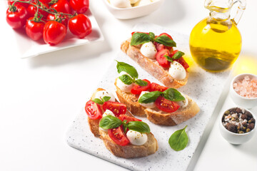Tomato, basil and mozzarella cheese fresh made caprese bruschetta. Italian tapas, antipasti with vegetables, herbs and oil on grilled ciabatta and baguette bread. Open sandwich.