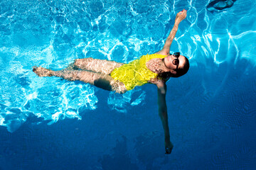 Shot from above of woman in a yellow swimsuit swimming in the pool