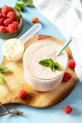 Protein shake with fresh berries. Fresh milk, raspberries drink on wooden board on a stone background.